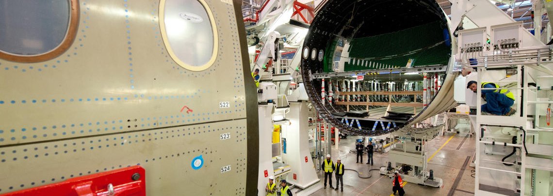 Fuselage sections of an Airbus A350 are combined on the factory floor under close supervision