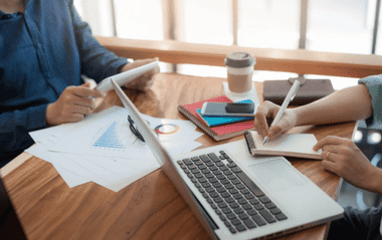 Two people sit at a table and work 